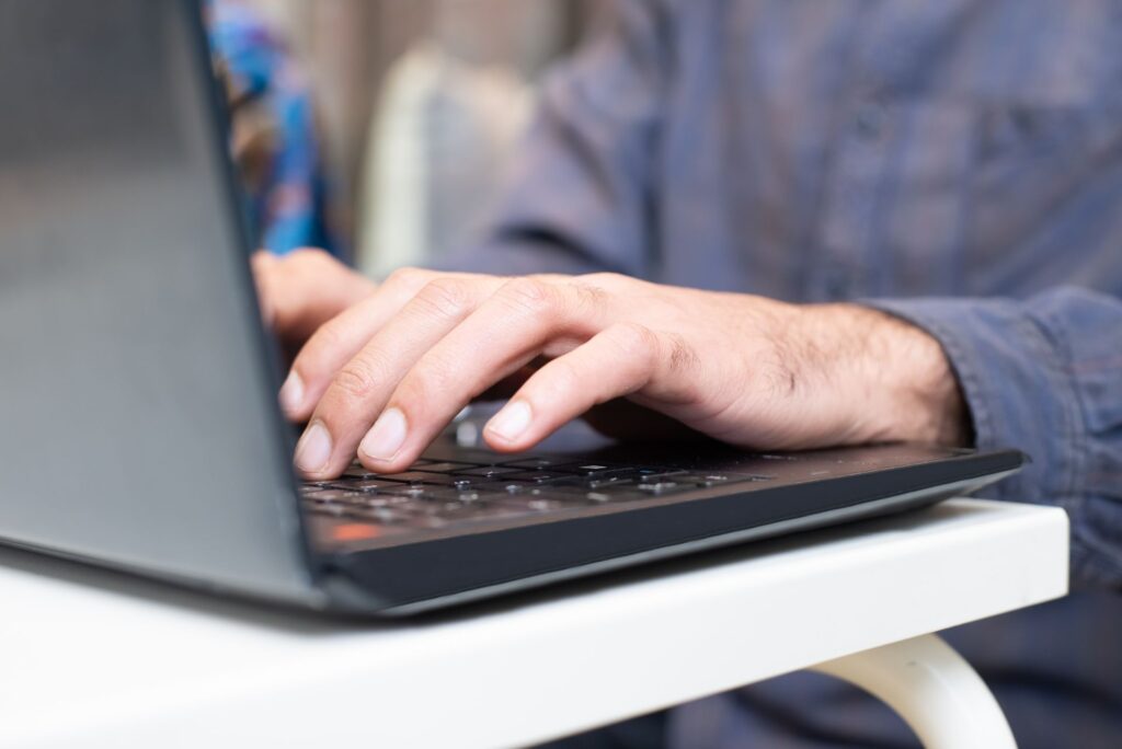 Close-up of hands typing on a laptop keyboard